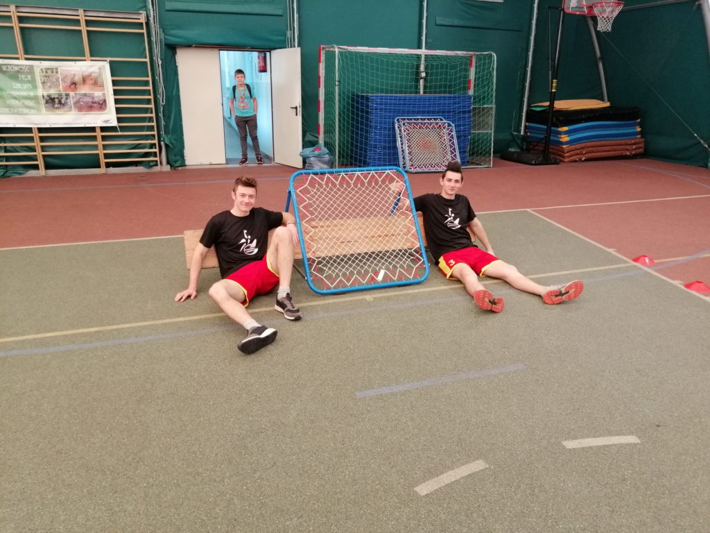 Zdjęcie: uczniowie Tchoukball Lubuskie siedzą przy bramce tchoukball. 