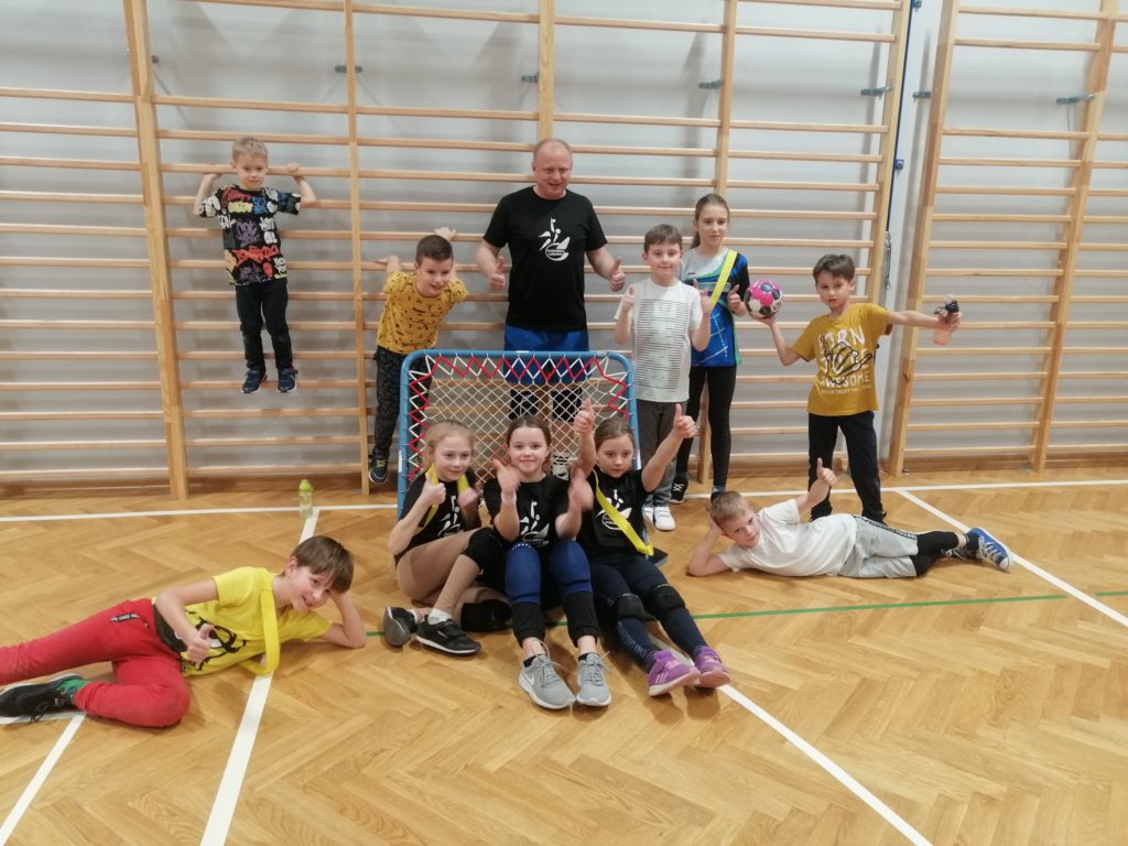 Dzieci z kciukami do góry na tle bramki do tchoukball. 